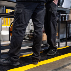 Focus sur la visibilité de la bande jaune de sécurité sur le tapis antifatigue en mousse haute densité.